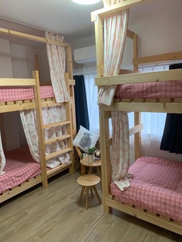 a room with three bunk beds and a table at ゲストハウス・東海　長良川 in Gifu