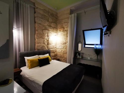 Un dormitorio con una cama con almohadas amarillas y una ventana en Central Boutique Hotel, en Jerusalén