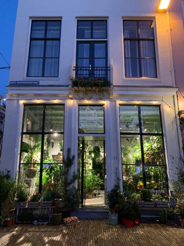 a white building with large windows and plants in it at Daen’s Greenhouse in Utrecht