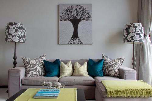 a living room with a couch and a tree picture on the wall at Shaloha Guesthouse on Supertubes in Jeffreys Bay