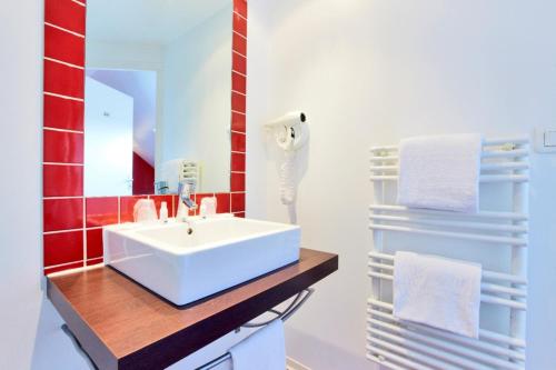 baño con lavabo blanco y azulejos rojos en KYRIAD ROUEN NORD - Mont Saint Aignan, en Mont-Saint-Aignan