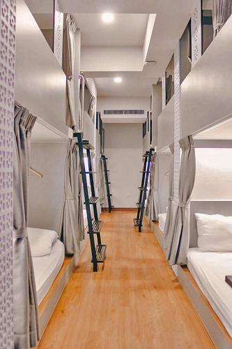 a room with four bunk beds and wooden floors at Capzule Bed Phuket in Phuket