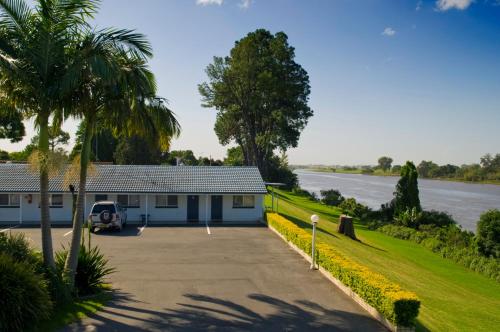 a house with a driveway next to a river at Colonial Court Motor Inn in Kempsey