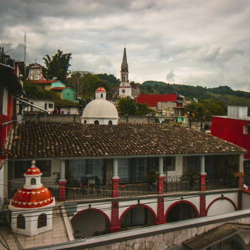 a building with a red roof in a city at Hotel Boutique TEKALI INN in Cuetzalán del Progreso