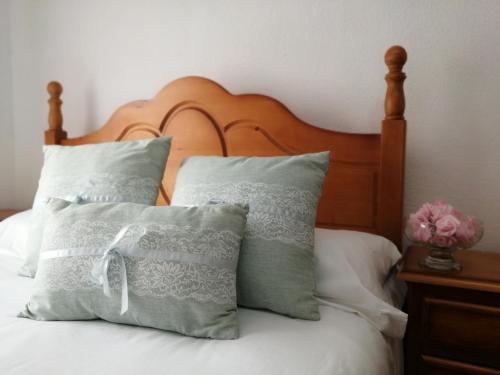 1 cama con almohadas blancas y cabecero de madera en La Casa de la Abuela María, en Baeza