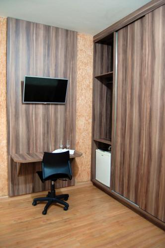 a room with a desk and a chair and a television at Solar Plaza Hotel in Fernandópolis