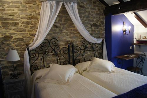 a bedroom with a bed with white sheets and curtains at La Casa Encanto in Espinosa de los Monteros