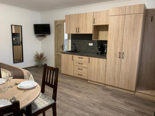 a kitchen with wooden cabinets and a table and a dining room at Varga Vendégház in Sümegprága