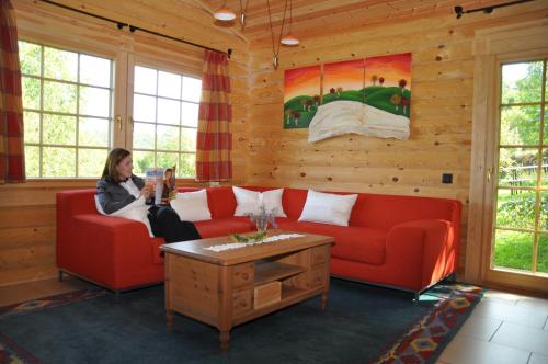 Eine Frau, die auf einer roten Couch im Wohnzimmer sitzt. in der Unterkunft Hotelanlage Country Lodge in Arnsberg