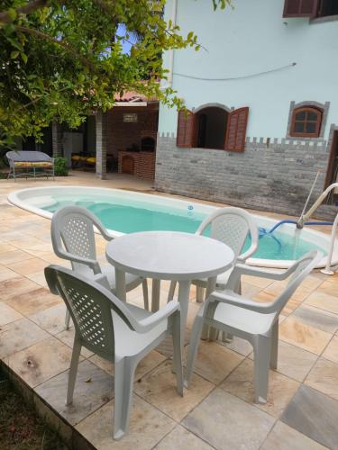 uma mesa e cadeiras ao lado de uma piscina em Casa a 3 minutos da praia em Saquarema