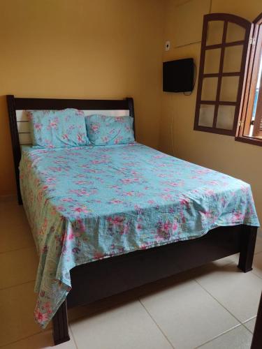 um quarto com uma cama com um edredão floral em Casa a 3 minutos da praia em Saquarema