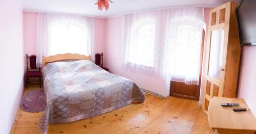 a bedroom with a bed and two large windows at Cottage Gutsulia in Yaremche