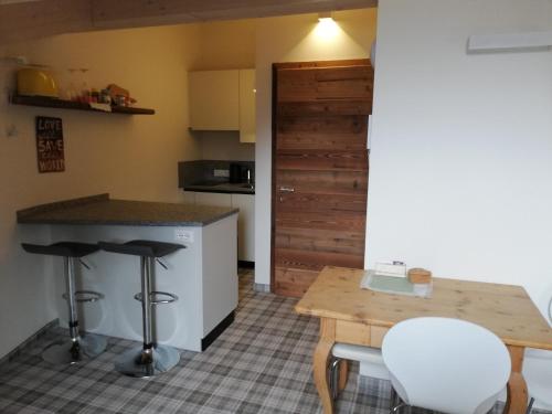 cocina con encimera, mesa y taburetes en Casa Lassù., en Carano
