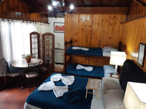 a room with two beds and a couch and a table at Villa Valentina chalés com lareira e churrasqueira in Campos do Jordão