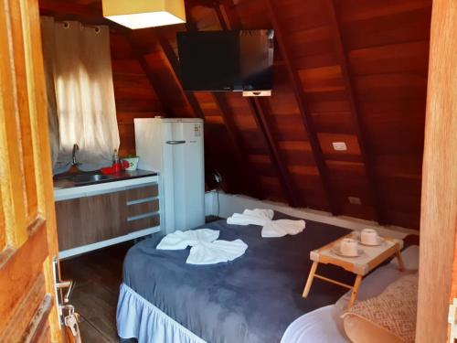 a room with two beds and a refrigerator and a table at Villa Valentina chalés com lareira e churrasqueira in Campos do Jordão