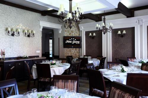 a dining room with white tables and chairs and chandeliers at Hotel Galany in Rădăuţi