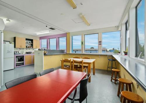 a kitchen with a red table and chairs in a room at Point Break Backpackers in Christchurch