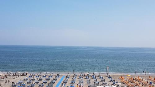 una playa con sillas y sombrillas y el océano en Abahotel, en Milano Marittima