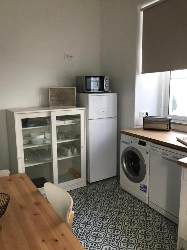 uma cozinha com uma máquina de lavar e secar roupa e uma mesa em Silvirhouse em Peniche