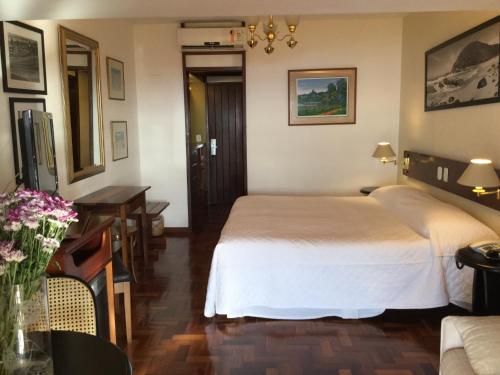 a hotel room with a bed and a table and a desk at Hotel El Cazar in Búzios