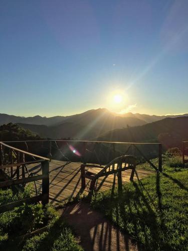 a bench sitting on top of a hill with the sunset at Recanto das Estrelas in Aiuruoca