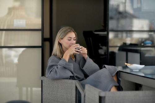 a woman sitting in a chair drinking a drink at Assemblage Boutique in Tel Aviv