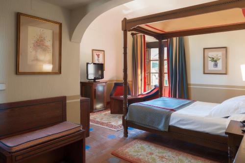 a bedroom with a canopy bed and a television at Parador de Oropesa in Oropesa