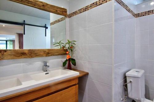 Un baño con lavabo, inodoro y espejo. en la rose, en Lamentin