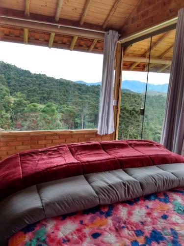 a bed in a room with a large window at Recanto das Estrelas in Aiuruoca