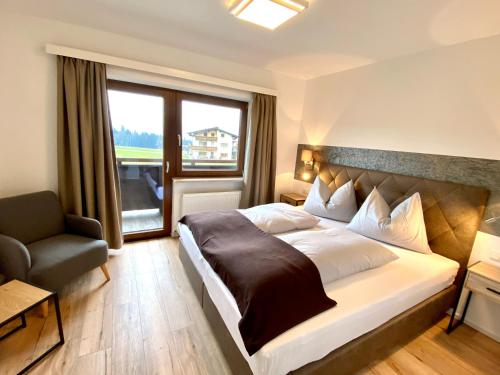 a bedroom with a bed and a chair and a window at Appartement Haus Seerose in Reith im Alpbachtal