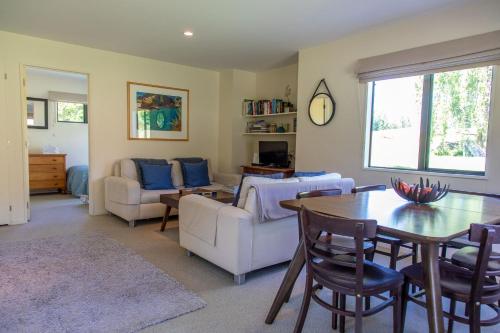 sala de estar con mesa, sillas y sofá en Arrowtown Country Cottage, en Arrowtown