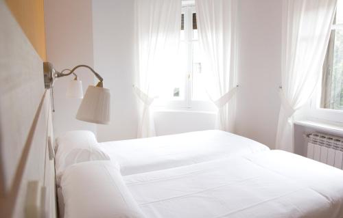 Cama blanca en habitación con ventana en Hostal Boreal Mistral, en Burgos