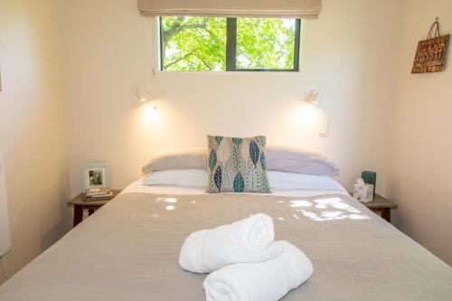 1 dormitorio con 1 cama con toallas en Arrowtown Country Cottage, en Arrowtown