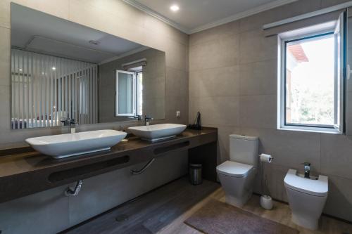 a bathroom with two sinks and a toilet at EPHYRUS - Country House, Restaurant, Wellness in Setúbal