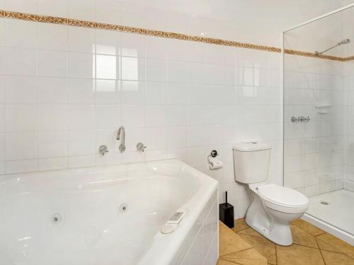 La salle de bains blanche est pourvue d'une baignoire et de toilettes. dans l'établissement Beachfront Penthouse Cowes, à Cowes