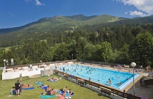 une grande piscine avec des personnes assises dans l'herbe dans l'établissement Valmorel Studio Skis aux pieds, à Valmorel