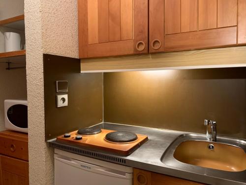 a kitchen with a sink and a cutting board on a counter at Valmorel Studio Skis aux pieds in Valmorel