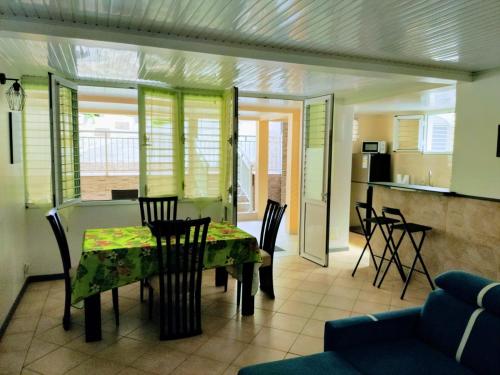 uma sala de jantar e cozinha com mesa e cadeiras em Dany Lodge - Spacieux T2 à 5 minutes de la plage en voiture em Rivière-Pilote