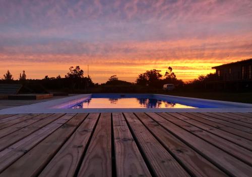 an empty swimming pool with a sunset in the background at Hus Punta Rubia in La Pedrera