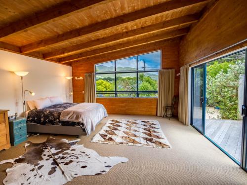 a bedroom with a bed and a large window at Mohua - Pakawau Holiday Home in Pakawau