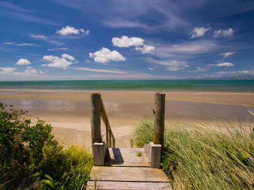 a wooden path to the beach with a view at Mohua - Pakawau Holiday Home in Pakawau