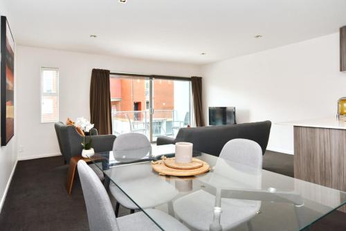 a dining room with a glass table and chairs at Armagh Apartment 3 - Christchurch Holiday Homes in Christchurch