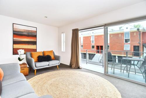 a living room with a couch and a large window at Armagh Apartment 3 - Christchurch Holiday Homes in Christchurch