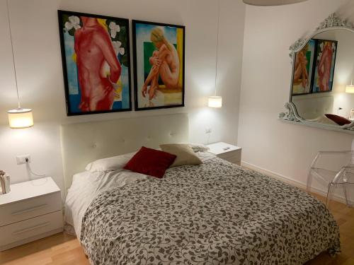 a bedroom with a bed and paintings on the wall at Casa Sauro in Campobello di Licata