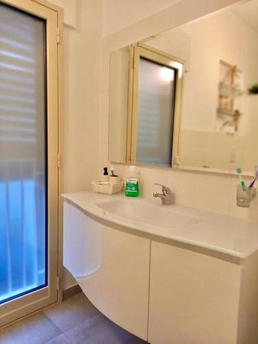 a white bathroom with a sink and a mirror at Casa Sauro in Campobello di Licata