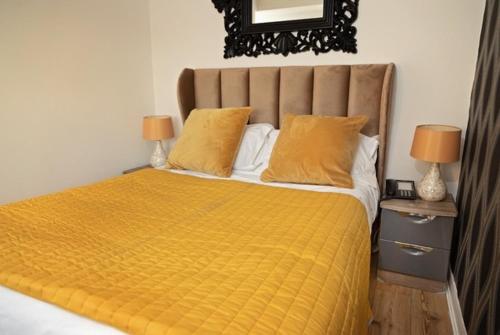 a bedroom with a large yellow bed with two lamps at G Boutique Hotel in Portsmouth