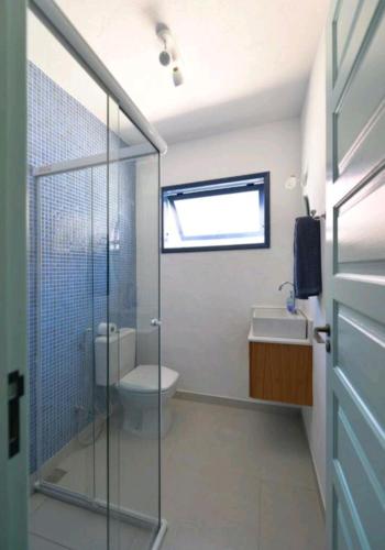 a bathroom with a toilet and a glass shower at Casa Boutique Peró in Cabo Frio