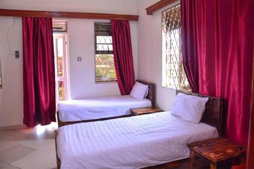 2 Betten in einem Zimmer mit roten Vorhängen in der Unterkunft Apartment in the city of Kampala in Kampala