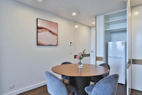 a dining room with a table and chairs and a refrigerator at Next to 'The Glen Shopping Centre' Apartment in Glen Waverley
