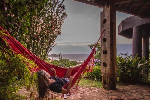 a woman laying in a hammock looking at the ocean at Villa Buena Vista in Praia do Rosa